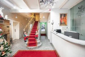 un long couloir avec un escalier en moquette rouge et un arbre de Noël dans l'établissement Art Hotel, à Druskininkai