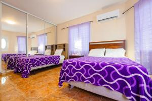 - 2 lits dans une chambre avec des draps et des miroirs violets dans l'établissement Big Vacation House, à Moca