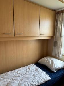 1 dormitorio con 1 cama y armarios de madera en Kobbe, en Ballum