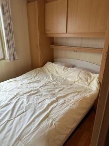 an unmade bed in a room with wooden cabinets at Kobbe in Ballum