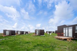 une rangée de conteneurs de transport noir dans un champ dans l'établissement Tiny House Nature 5 Innenlage - Green Tiny Village Harlesiel, à Carolinensiel