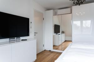 een witte slaapkamer met een flatscreen-tv en een bed bij Modern stylish design apartment with free parking Emily in Wenen