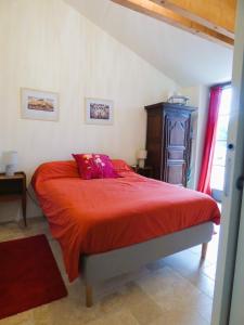 a bedroom with a bed with a red blanket at Le Petit Pré, Gîte chez l'habitant in Gizeux