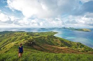 uma mulher no topo de uma colina com vista para o oceano em S@fe Landing Lodge em Nacula Island