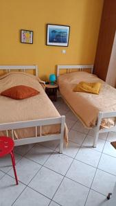 two beds sitting in a room with a tiled floor at Maria's rooms CHANTZARA SPYROPOULOS Flats to Let-City Center in Igoumenitsa