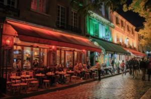 a group of people sitting at tables on a street at night at 1 Chambre Arena - La Chapelle in Paris