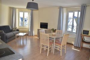 - un salon avec une table, des chaises et un canapé dans l'établissement Résidence Le Rochebonne, à Saint-Malo