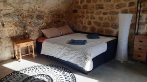 1 dormitorio con 1 cama en una pared de ladrillo en Le Pas Sage au Trible, Suites Bambou/ La Source/ Tataouine, en Gluiras