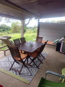 Une table et des chaises en bois sont disponibles sur la terrasse. dans l'établissement Map of Africa Luxury Caravan with private bathroom with sea view, à Wilderness