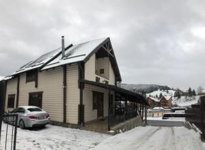 a house with a snow covered roof on a snowy street at Palaga Bukovel in Bukovel