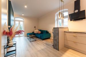 a living room with a blue couch and a kitchen at Apartament Smile - z prywatnym monitorowanym parkingiem by SpaceApart in Jelenia Góra