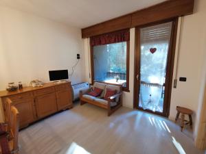 - un salon avec un canapé, une télévision et une fenêtre dans l'établissement Mountain View, à Castello Valsolda