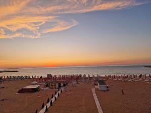 - une plage avec des chaises et des parasols au coucher du soleil dans l'établissement Hotel H, à Eforie Nord