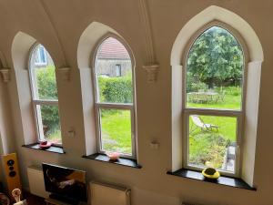 trzy okna w pokoju z widokiem na ogród w obiekcie Charmante chapelle aménagée à Eprave w mieście Rochefort