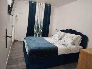 un letto con testiera blu in una camera da letto di Magnifique appartement au bord de la Seine avec parking a Villeneuve-la-Garenne