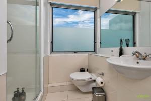 a bathroom with a toilet and a sink and a window at AWSA On the Water Luxury (4021) in Auckland