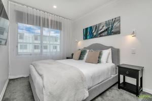 a white bedroom with a large bed and a window at AWSA On the Water Luxury (4021) in Auckland