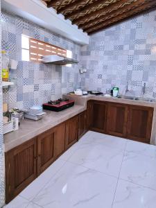 eine Küche mit Holzschränken und einer Kachelwand in der Unterkunft Joglo Wismono Prambanan in Prambanan
