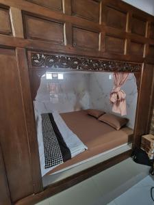 ein Bett in einem Holzrahmen mit einem Spiegel in der Unterkunft Joglo Wismono Prambanan in Prambanan