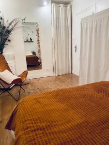 - une chambre avec un lit, une chaise et un miroir dans l'établissement La Maison D' hote du Fond Du Riu, à Allemans-du-Dropt