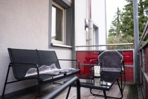 Klassen Apartments! Schnuckeliges Apartment - mit Balkon -in Bad Saulgau -für vier Personen - 1 OG في باد زاولغاو: كرسي أسود جالس على شرفة مع بطانية