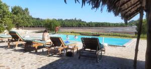a woman sitting in chairs by a swimming pool at Emeraude Lodge in Andilana