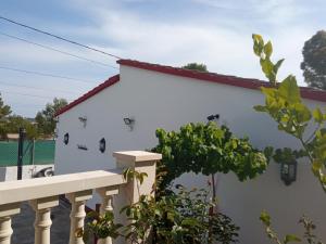 une maison blanche avec une clôture et un arbre dans l'établissement Els Rosers - con jacuzzy XL y barbacoa, à Rodonyà