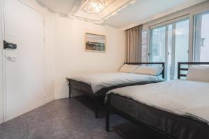 two beds in a room with a window at KOTARO HOUSE in Seoul