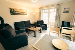 uma sala de estar com um sofá, cadeiras e uma mesa em Haus Seeschwalbe em Spiekeroog