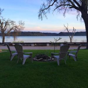 drie stoelen en een tafel in het gras bij een meer bij Villa Del Lago - Lakehouse in Pepin in Pepin