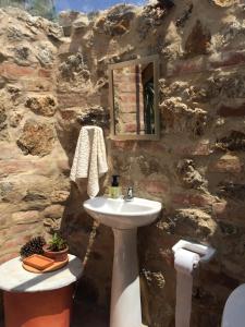 La salle de bains est pourvue d'un lavabo et d'un mur en pierre. dans l'établissement The Little Glass House, à Villa de Leyva