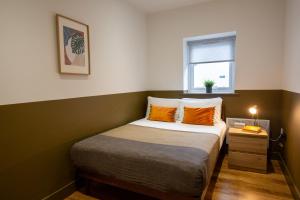 um quarto com uma cama com almofadas laranja e uma janela em RWST Holiday Lodges em Llanrwst