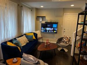 uma sala de estar com um sofá azul e uma televisão em Knight Campbell Carriage House em Denver