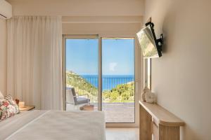 a bedroom with a bed and a view of the ocean at Elianes Villas in Anomeriá