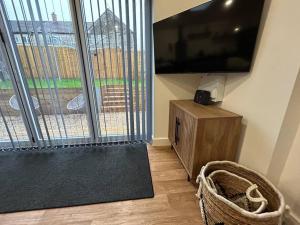 a living room with a flat screen tv and a large window at New Build Cosy Bungalow near Bath and Bristol in Wick