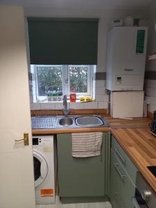 a kitchen with a sink and a washing machine at Cozy House, Garden, Free Parking, Opposite Train station with Disneyplus & Netflix included in West Thurrock