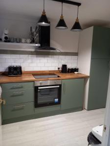 a kitchen with green cabinets and a stove top oven at Cozy House, Garden, Free Parking, Opposite Train station with Disneyplus & Netflix included in West Thurrock