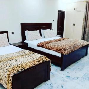 Hotel Sky Inn Clifton في كراتشي: غرفة نوم بسريرين وملاءات فهد