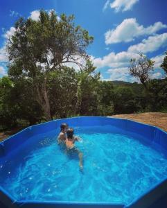 Dos personas nadando en una piscina azul en Casa Concha na Vila da Montanha en Gravatá