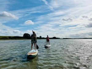 two people are standing on paddle boards in the water at Feriendorf Klein Stresow Rügen in Putbus