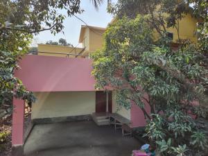 達卡的住宿－Aaira manjil1，一座有粉红色和黄色外墙和树木的建筑