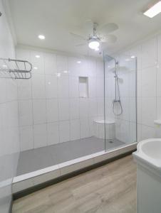 a white bathroom with a shower and a sink at The Chancellor Hotel in Port-of-Spain