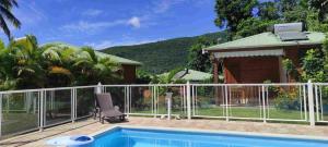 a house with a swimming pool with a fence at Le tri Haut de Bellevue - Bungalow Manguier in Pointe-Noire
