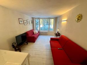 salon z czerwoną kanapą i telewizorem w obiekcie Monolocale Cristallo 20 - Serafini w Madonna di Campiglio