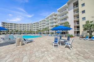 a large apartment building with chairs and a swimming pool at Destin West Gulfside Two Bedroom with Bunks!!! Lazy River!! in Fort Walton Beach