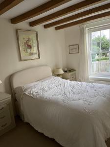 a bedroom with a white bed and a window at Luxury Brick and Flint House in Funtington in Chichester