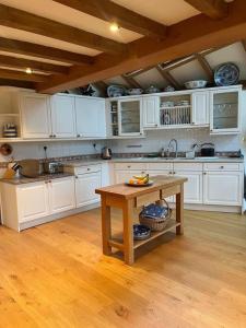 a kitchen with white cabinets and a wooden table at Luxury Brick and Flint House in Funtington in Chichester
