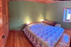 Schlafzimmer mit einem großen Bett mit blauer Decke in der Unterkunft Casa in centro storico stile chalet di montagna in Ovindoli
