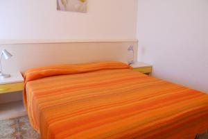 un letto in una stanza con una coperta arancione sopra di Bright flat with a wide terrace - Beahost Rentals a Bibione