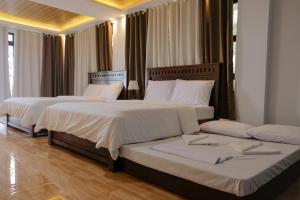 two beds in a hotel room with white sheets at Saffire Beach Resort and Glamping in Pagudpud